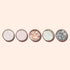 Five round Manucurist Blush biodegradable glitter containers, ideal for nail art, are lined up on a beige background. Their textures and colors range from white and pale pink sparkle to gold and silver glitter.