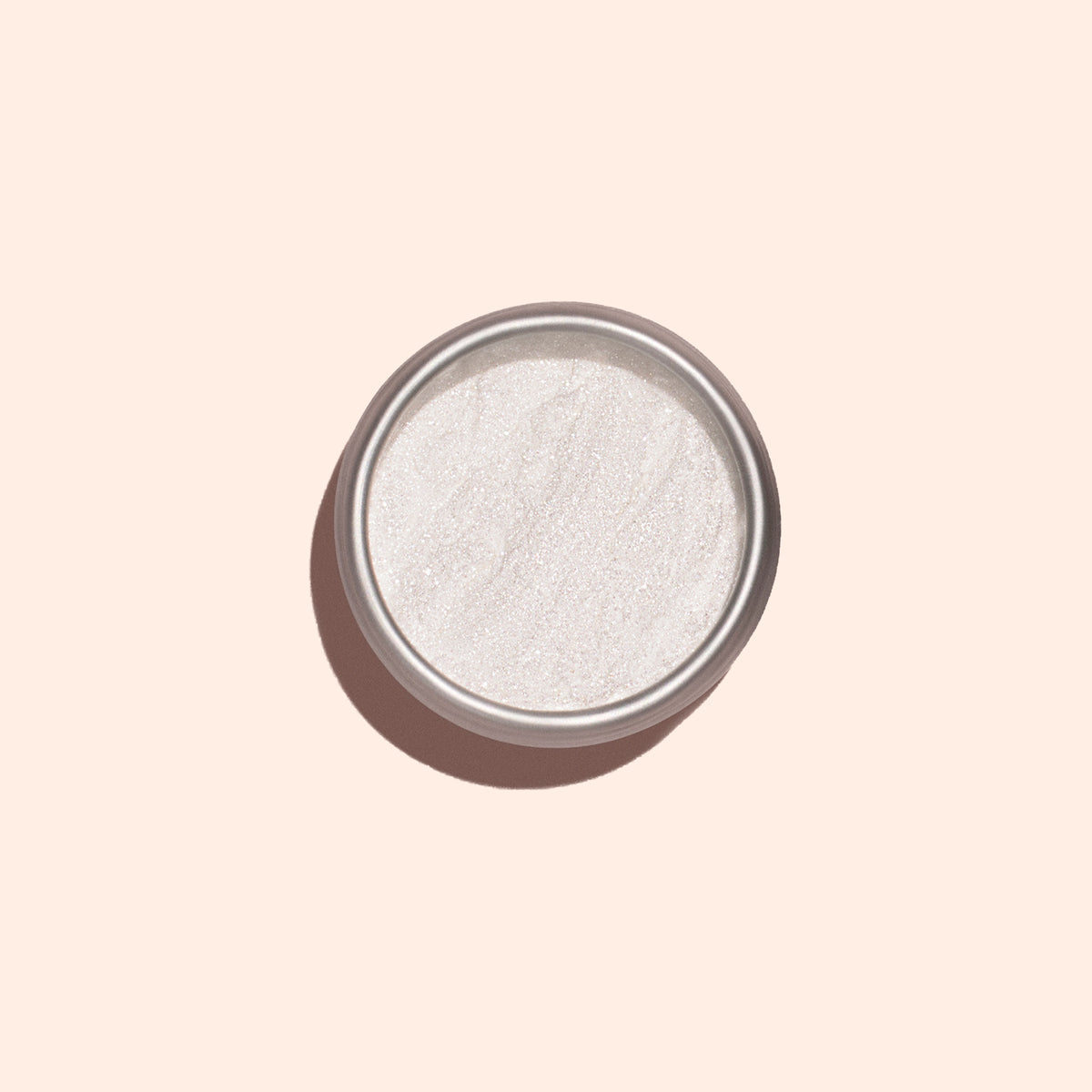 A round tin of Manucurist White Glazed Effect Powder sits on a pale beige background, its fine white shimmer perfect for achieving a glazed finish on manicures. The container casts a soft shadow to the left.