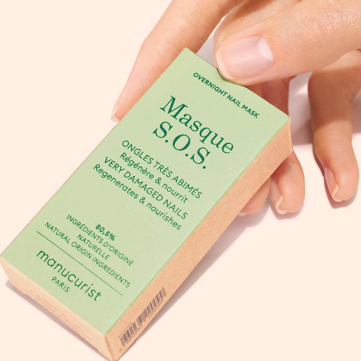 A hand holds a green box labeled S.O.S. Nail Mask by Manucurist, an overnight nail treatment with natural origin ingredients designed to regenerate and repair very damaged nails.