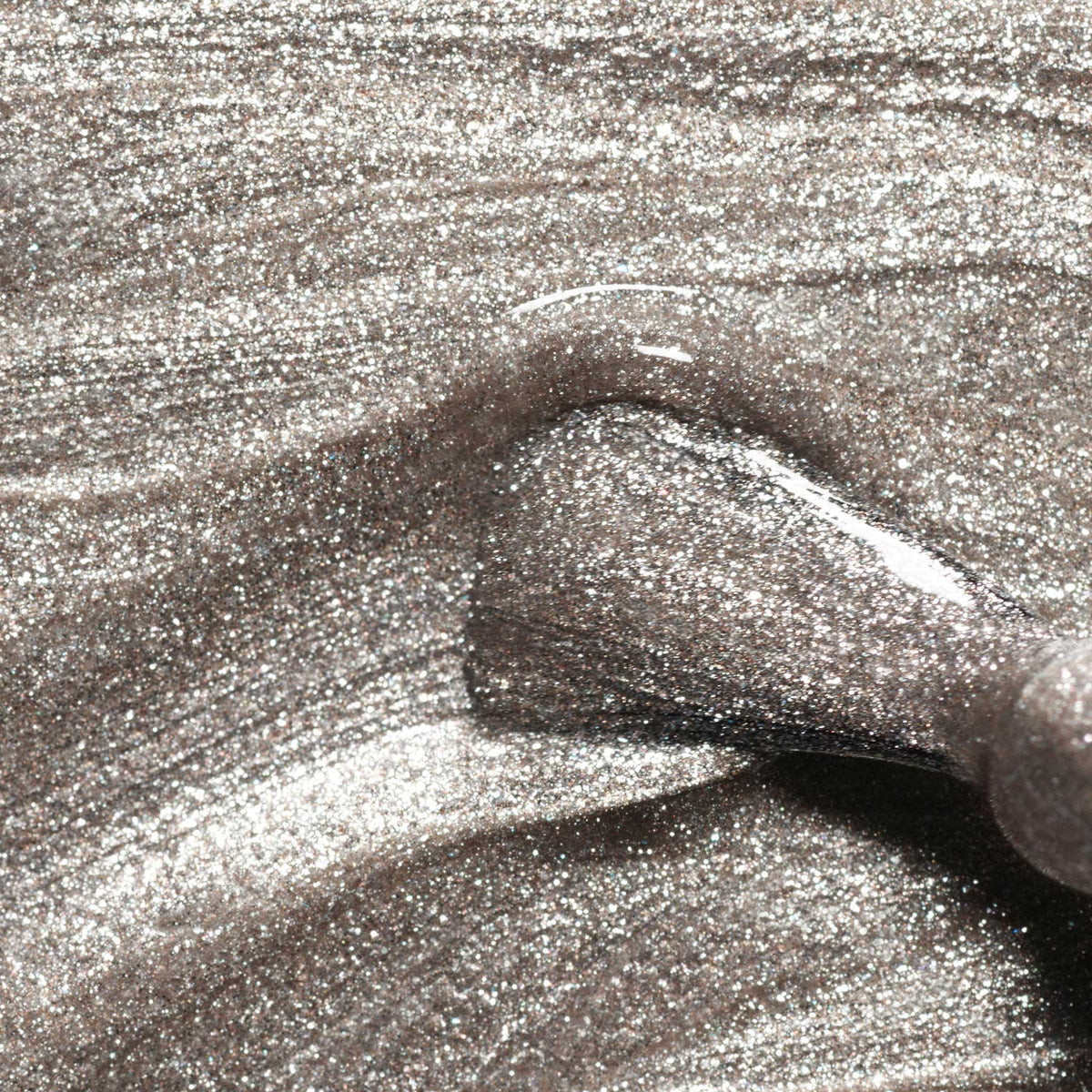 Close-up of a Manucurist Shiny Summer Nail Art Brush applying metallic silver polish with fine glitter for smooth, shimmery streaks.