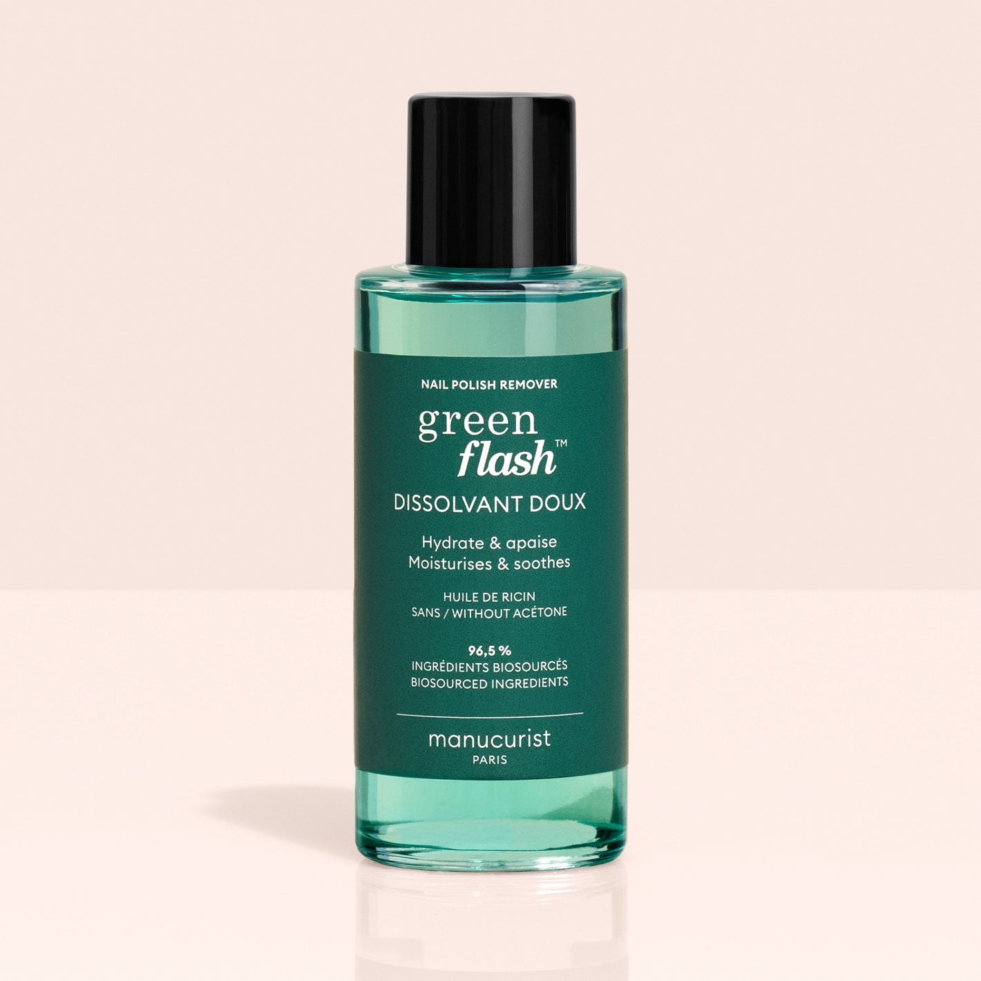A bottle of Manucurist Green Flash™ Gel Polish Remover, featuring a black cap and green liquid, with a label highlighting its moisturizing, soothing formula ideal for removing gel polish.