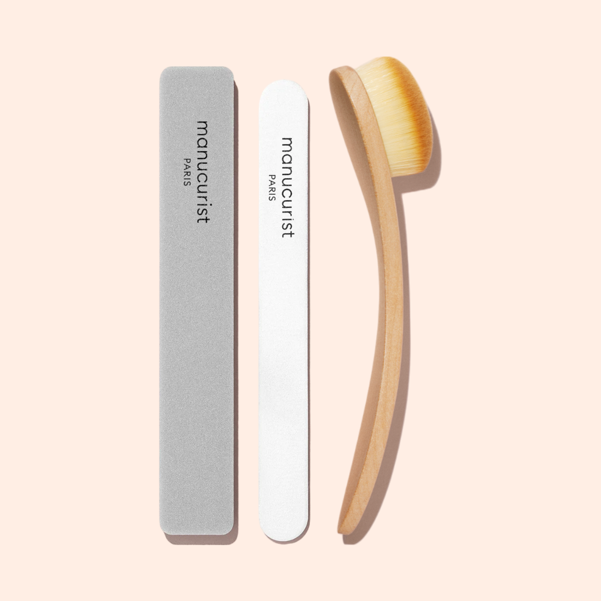 The Manucurist Nail Buffer Sponge and a wooden nail brush with soft bristles, both labeled “Manucurist,” are arranged vertically on a light beige background.