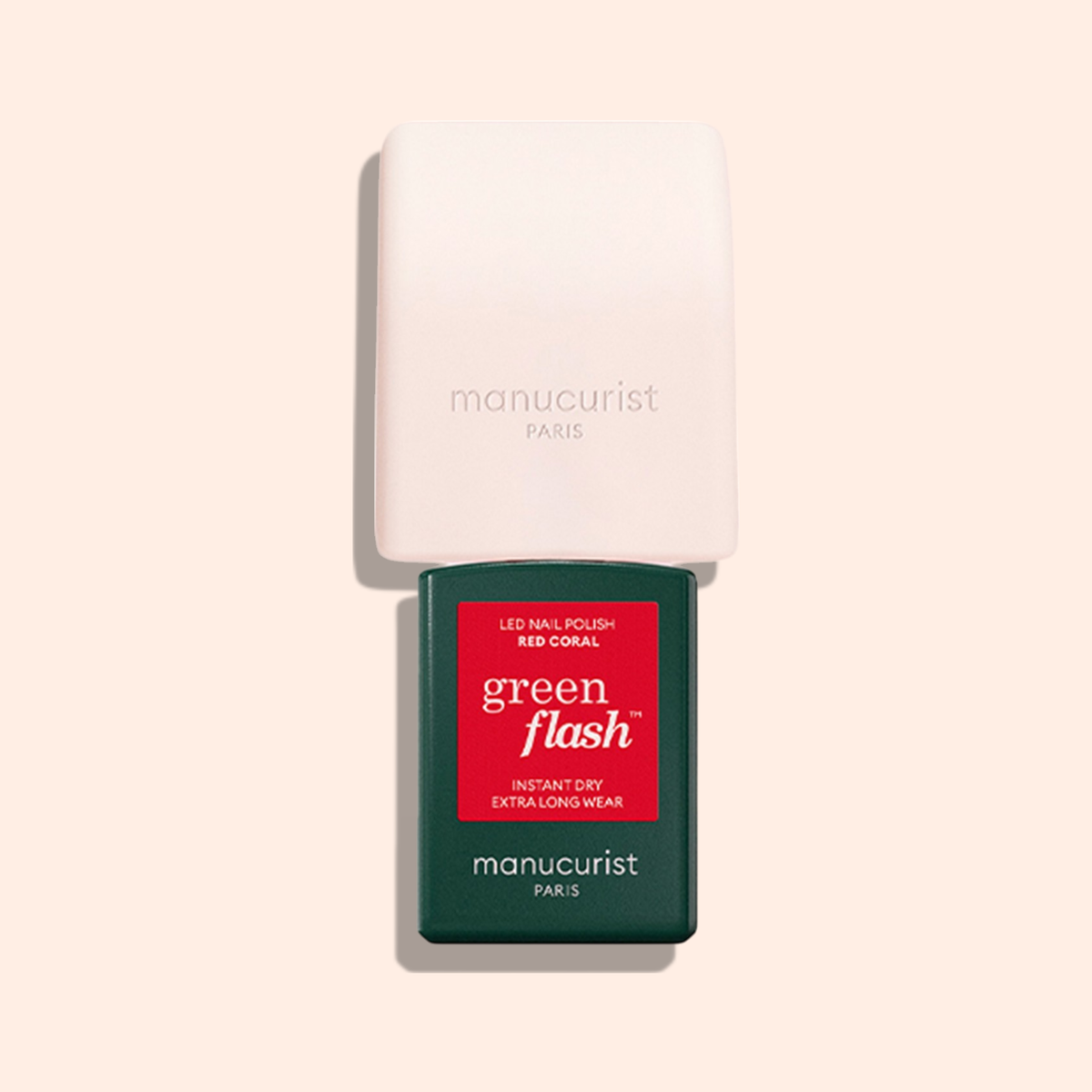 The Manucurist Mani Helper and a green bottle of Manucurist Green Flash red coral polish are arranged vertically on a light beige background, ideal for a perfect manicure.