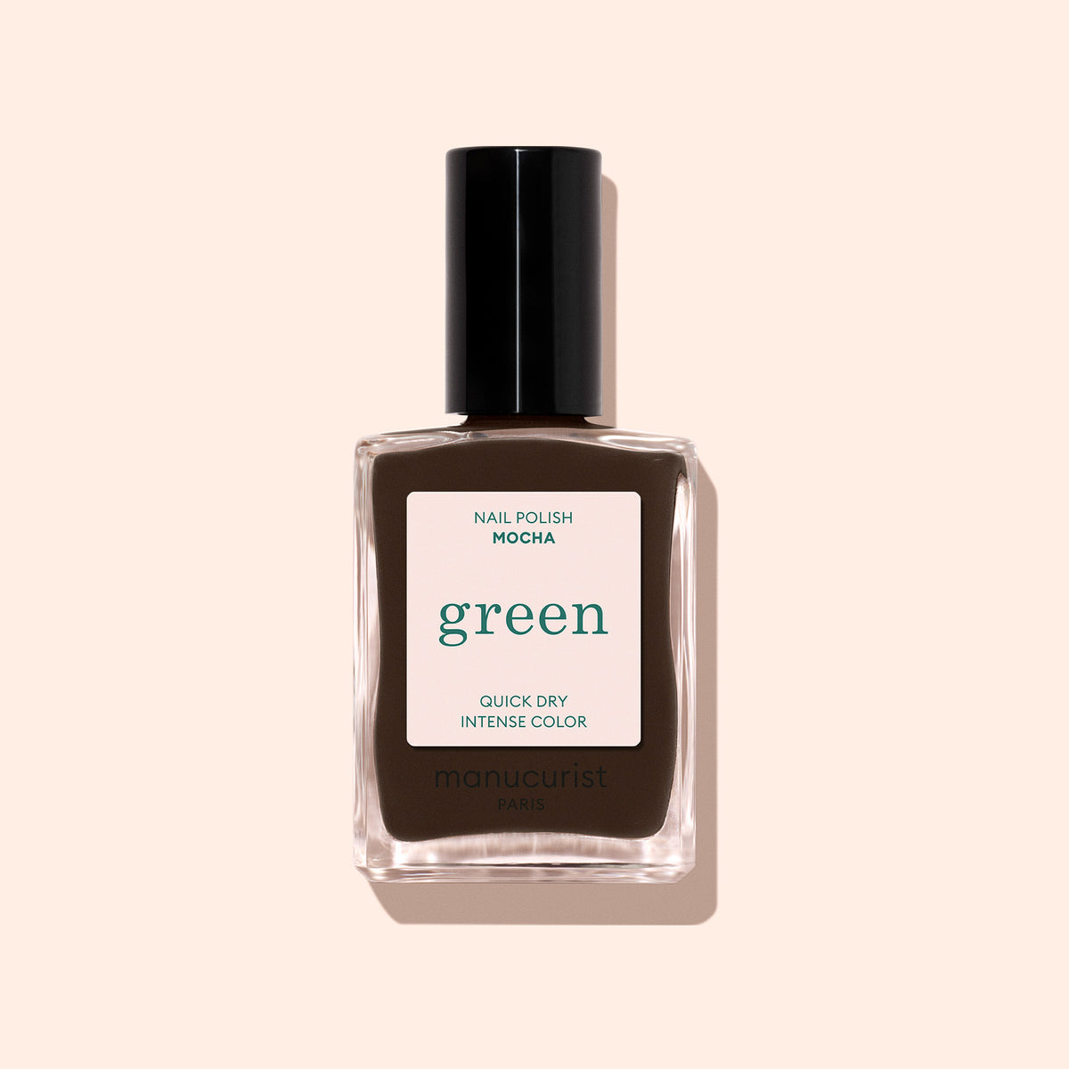 A bottle of Manucurist Mocha nail polish in dark brown with cool undertones and quick-dry, intense color. The polish features a black cap and is displayed against a pale beige background.