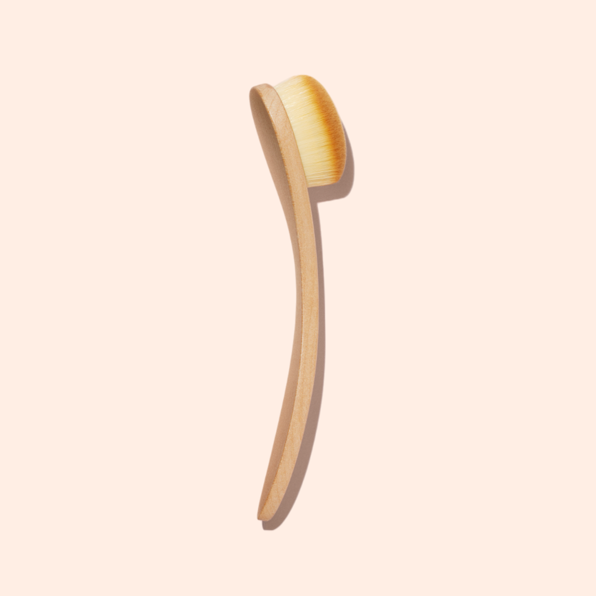 The Manucurist Dust Brush, featuring dense, soft vegan bristles and a long wooden handle, is designed for gentle nail surface cleaning. It is displayed against a light beige background.