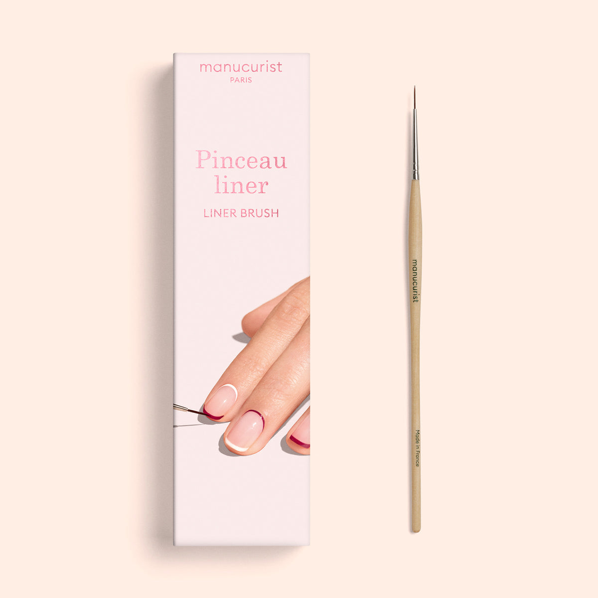 A professional-quality Manucurist Liner Brush and its box. The packaging displays a hand with manicured nails using the Liner Brush, emphasizing its vegan synthetic bristles. Printed on the box are “Pinceau liner,” “Liner Brush,” and the brand name Manucurist PARIS.