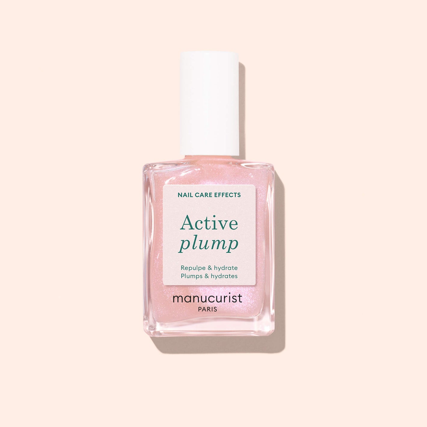 A bottle of Manucurist Active Plump collagen nail polish, featuring shimmery pink color and a white cap, is shown against a pale pink background for beautifully hydrated nails.