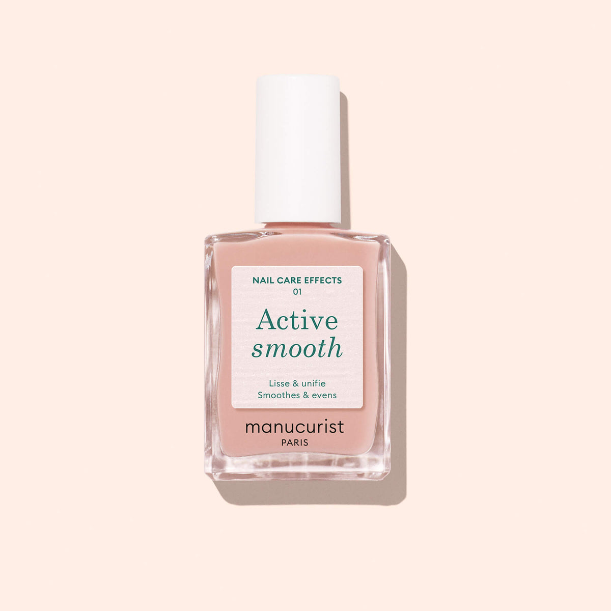 A bottle of Manucurist Active™ Smooth 01 nail care polish with a white cap, filled with light pink plant-based liquid, is displayed on a pale peach background.