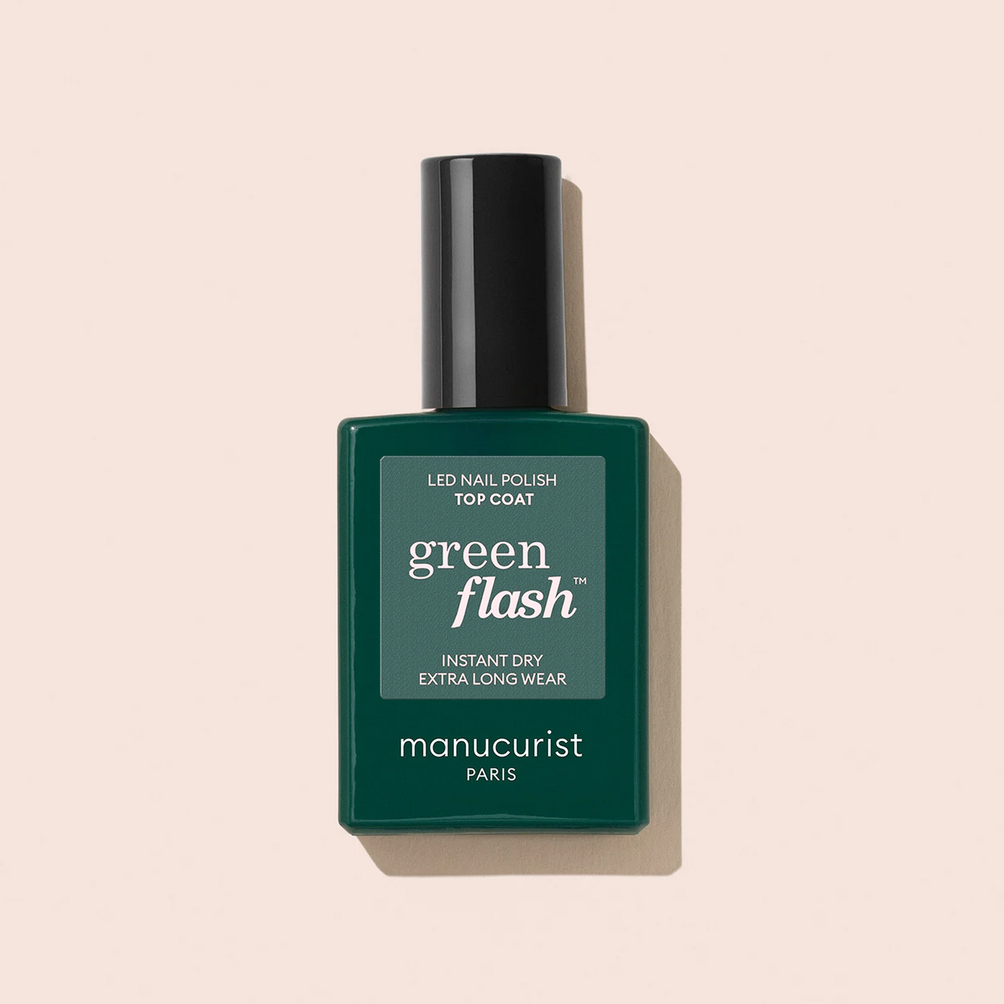 A bottle of Manucurist Top Coat Green Flash™ gel polish with a dark green label and black cap is shown against a light beige background, offering up to 12-day shine.