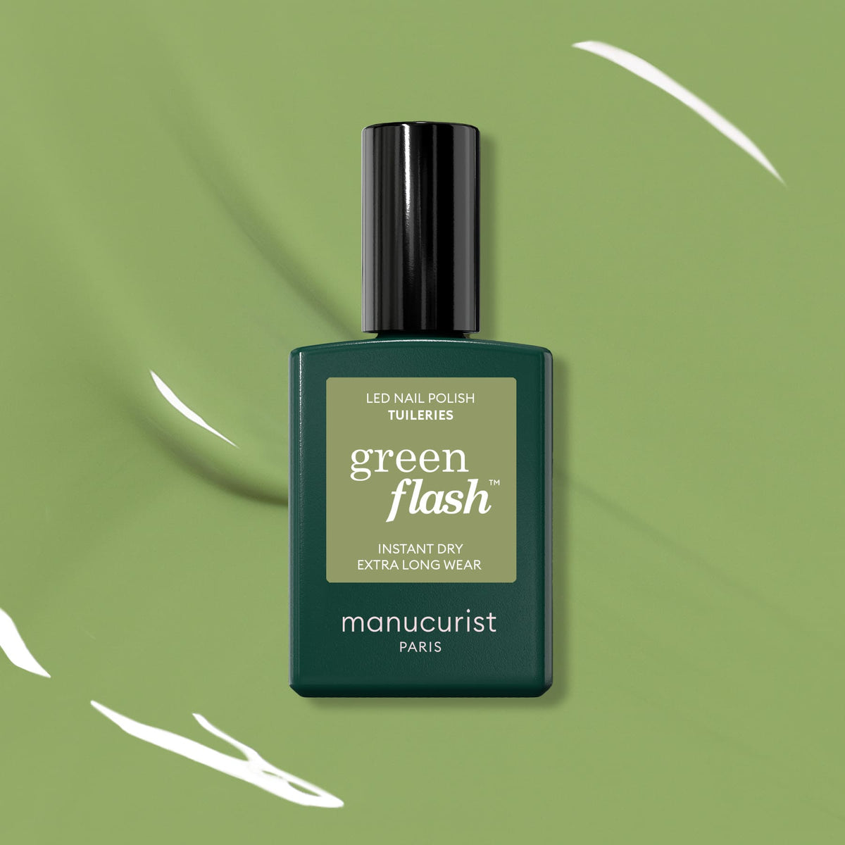 A bottle of Manucurist Tuileries Green Flash LED Gel Polish sits centered on a green background with white streaks. The dark olive-green bottle has a black cap and a beige label.