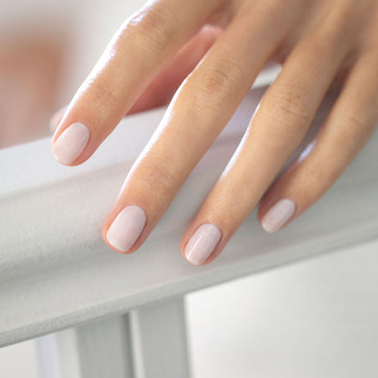 A hand with neatly manicured nails painted in Manucurist-test’s Milky white OLD gel nail polish rests gently on a white surface, offering a soft, elegant look that is easy to remove.