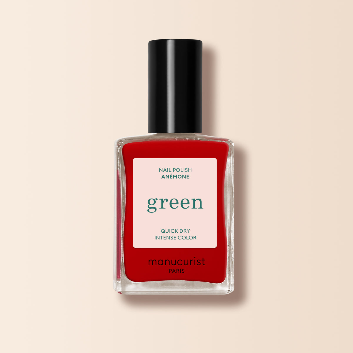 Manucurist Anémone nail polish features a juicy red hue, a black cap, and beige background, with "Quick Dry Intense Color" on the label. Part of the Green range.