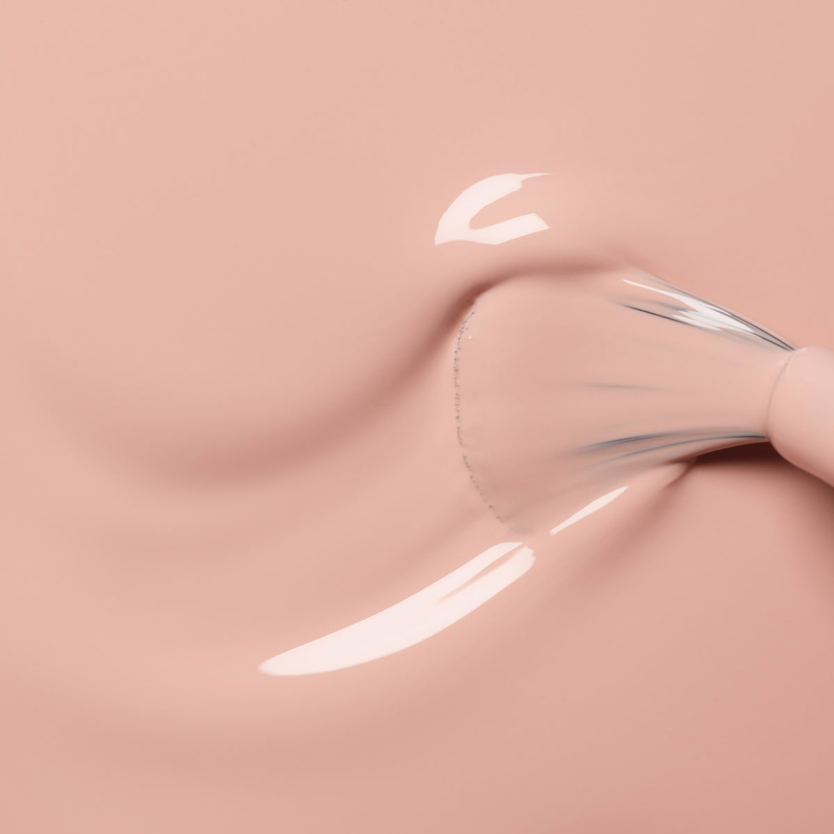 A close-up of a Manucurist Dune brush applying glossy, light pink shimmer nail polish on a smooth surface.