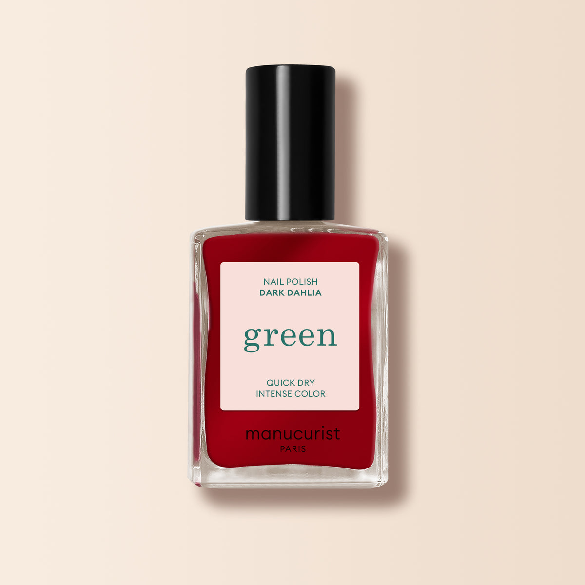 A bottle of Manucurist Dark Dahlia, a deep dark red nail polish from the Green™ range, featuring a black cap and a label reading "green, quick dry intense color.