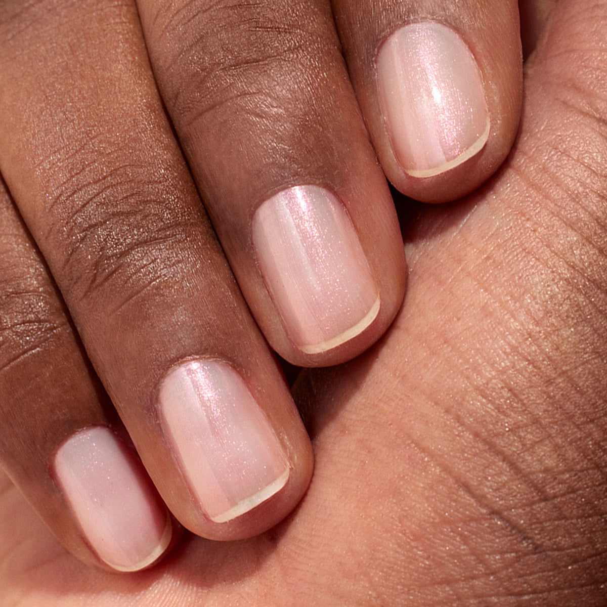 A close-up of neatly manicured nails with a natural, glossy look and subtle shimmer, achieved using Manucurist Pink Glazed Effect Powder for a sheer light pink, pearlescent finish.