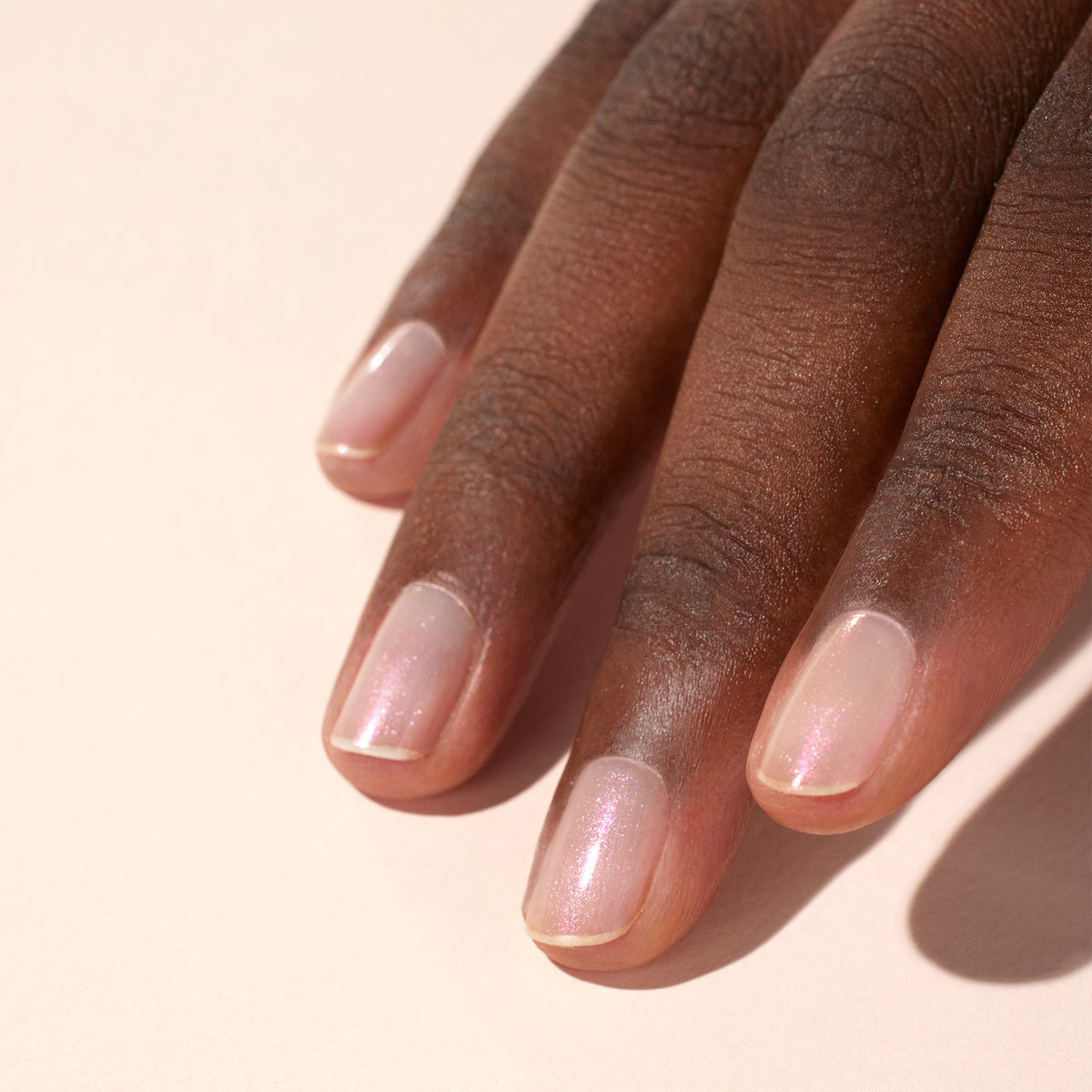 A close-up of a dark-skinned hand with neatly manicured nails, finished with Manucurist&
