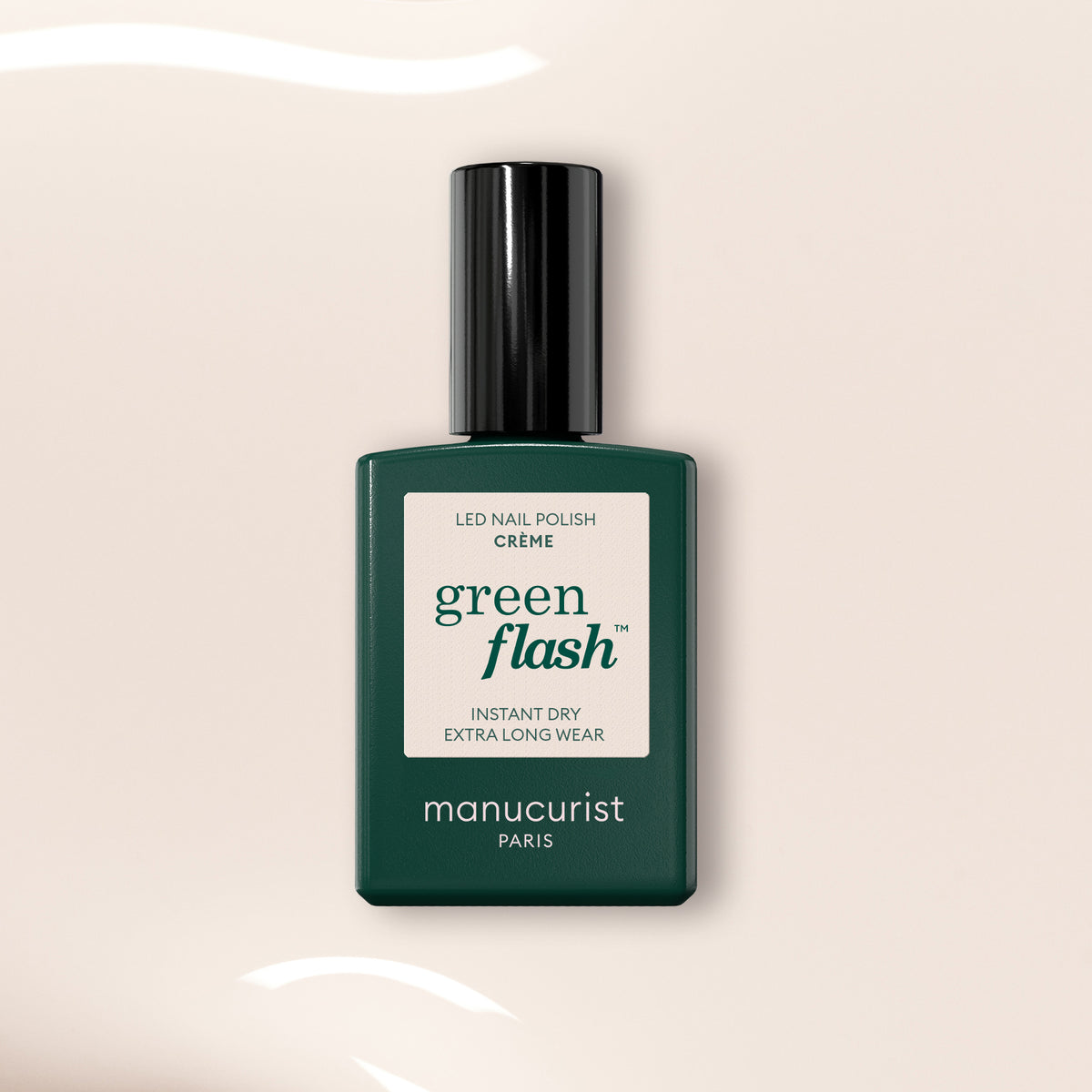 A bottle of Manucurist Crème gel polish with a dark green base and black cap is displayed against a light beige background featuring wavy white reflections.