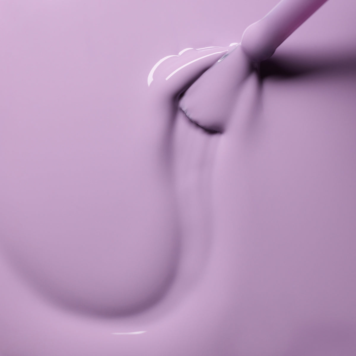 A close-up shows a brush applying Manucurist Lisa Lilas gel polish, creating a smooth, glossy lilac surface with visible brush strokes in the liquid polish.