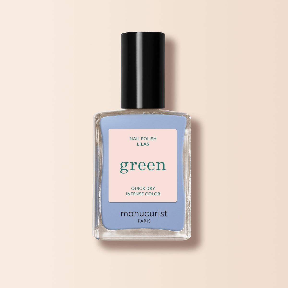 A bottle of Manucurist Lilas nail polish in a lilac shade features a black cap and pastel label reading "Nail Polish Lilas," "Quick Dry," and "Intense Color," set against a light beige background.