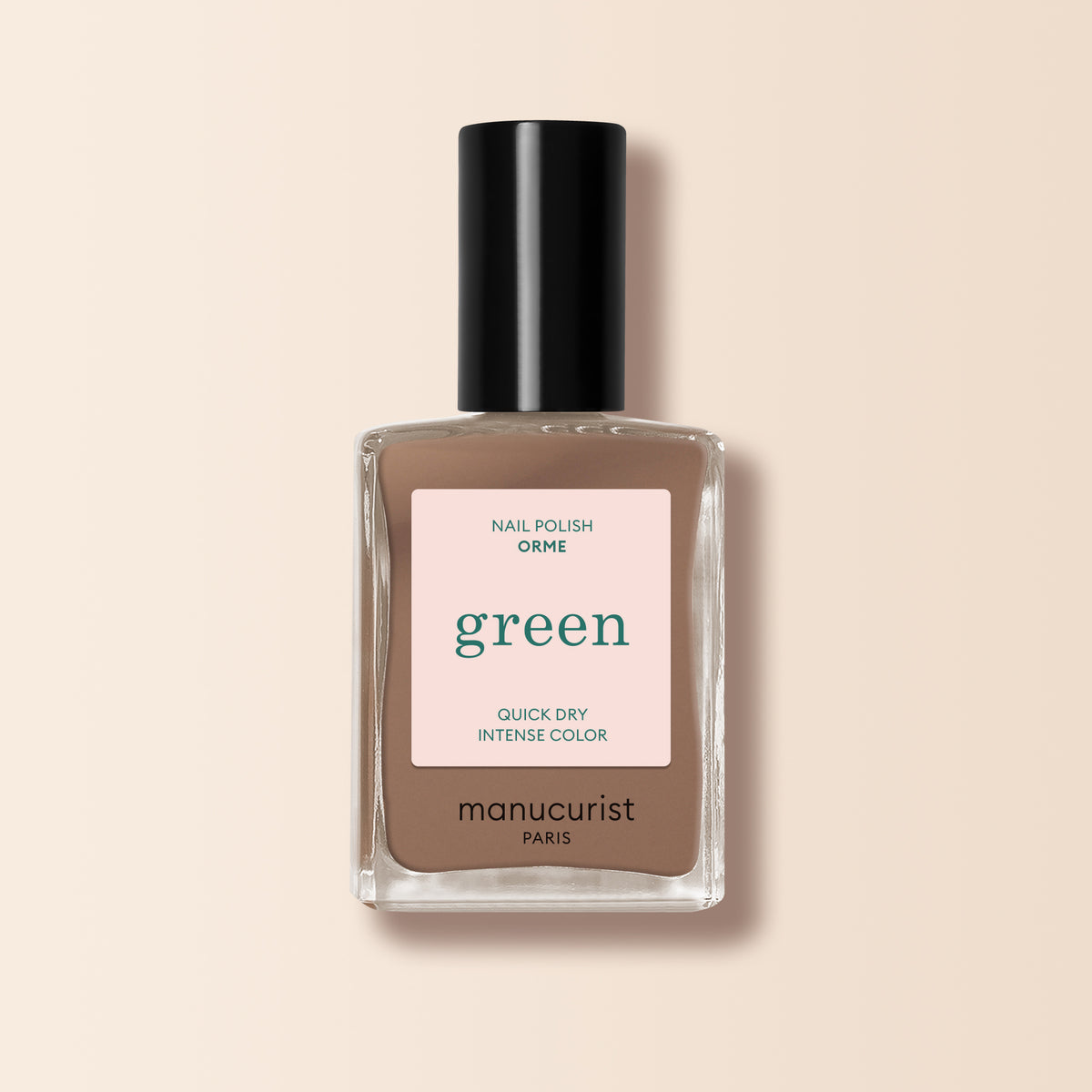 A bottle of Manucurist Orme nail polish from the Green range rests on a beige background, displaying its chic café au lait shade and stylish taupe-brown color. The label highlights: Orme, Green, Quick Dry, Intense Color.