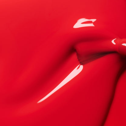 Close-up of Manucurist-test Red Coral OLD glossy LED nail polish being spread smoothly with a brush, revealing shiny highlights and rich, long-lasting color.