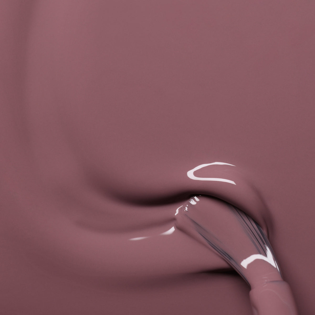 A close-up of Manucurist’s Rose Mountbatten gel polish being smoothly applied with a brush, revealing a glossy pinky taupe shade and luminous reflections.