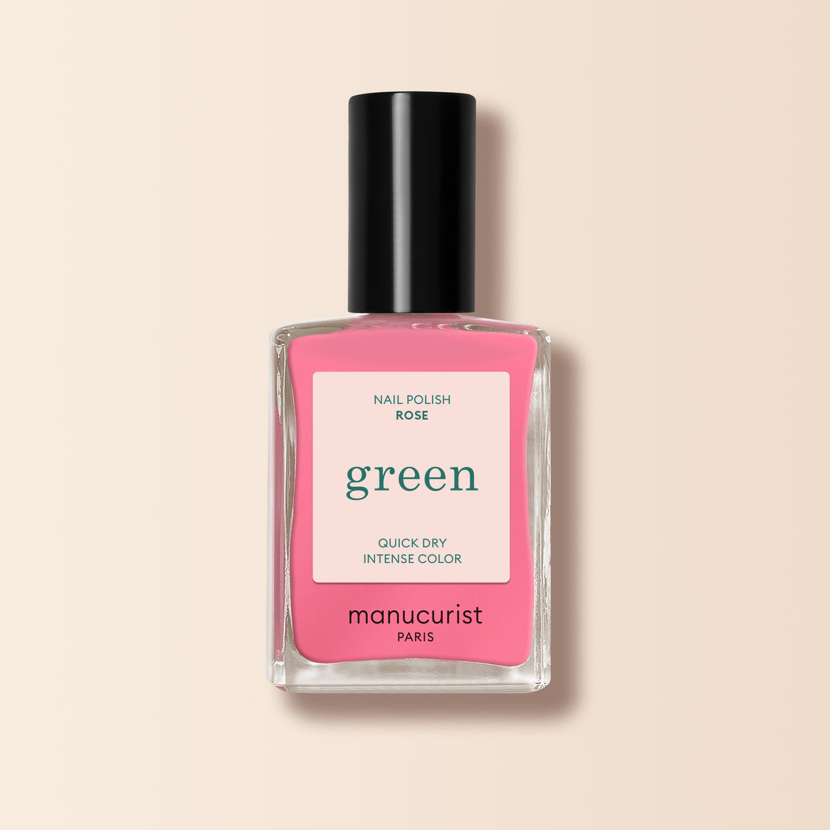 A clear glass bottle of bright pink "Rose" nail polish by Manucurist with a black cap, labeled "Quick Dry Intense Color" from the Green range, set against a soft beige background.
