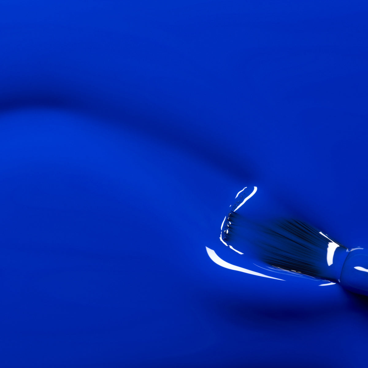A paintbrush with black bristles is partially visible in the lower right corner, spreading a smooth, glossy layer of Manucurist&