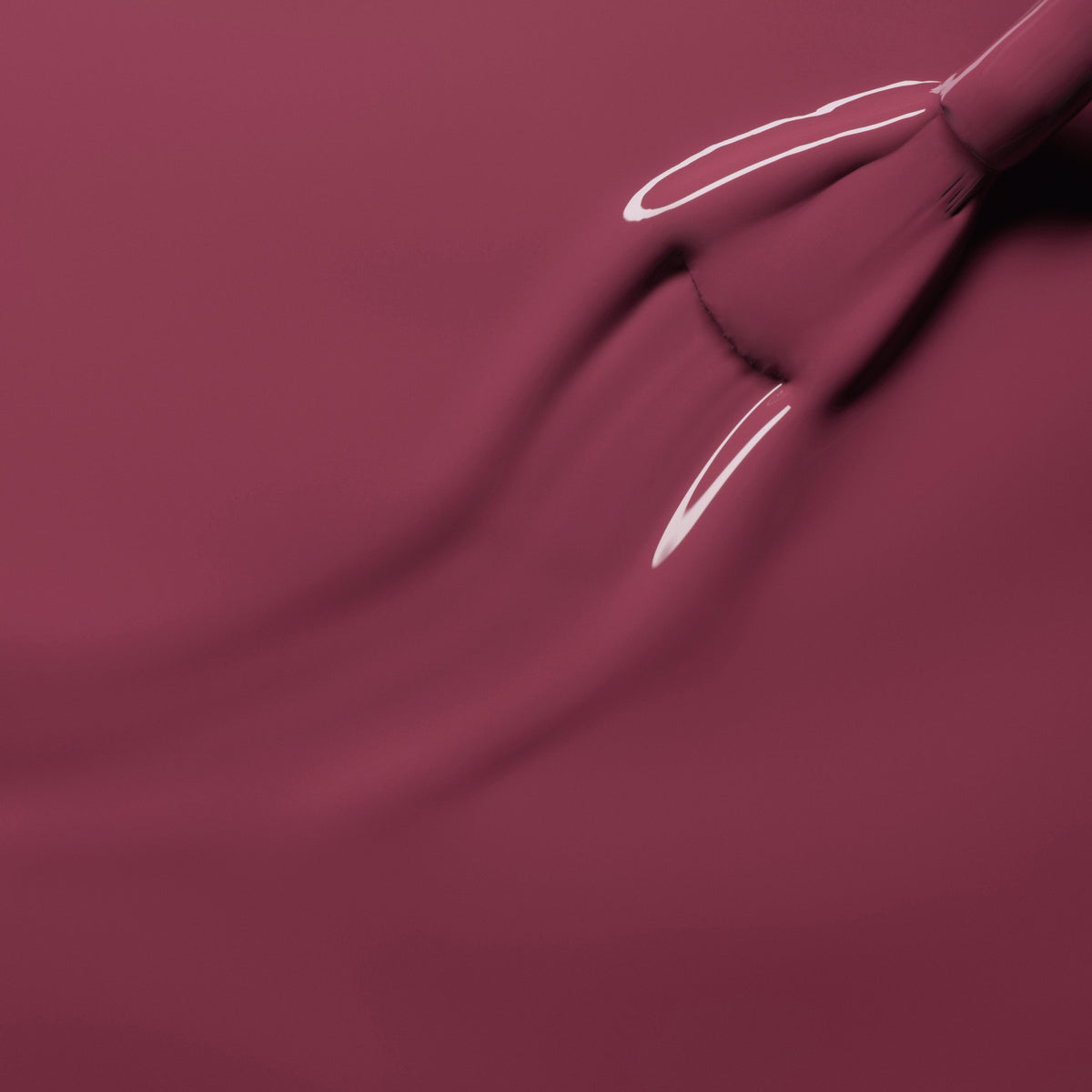 A close-up of a brush spreading Manucurist’s Victoria Plum Green Flash gel polish in a glossy layer, showing faint brush strokes and reflective highlights.