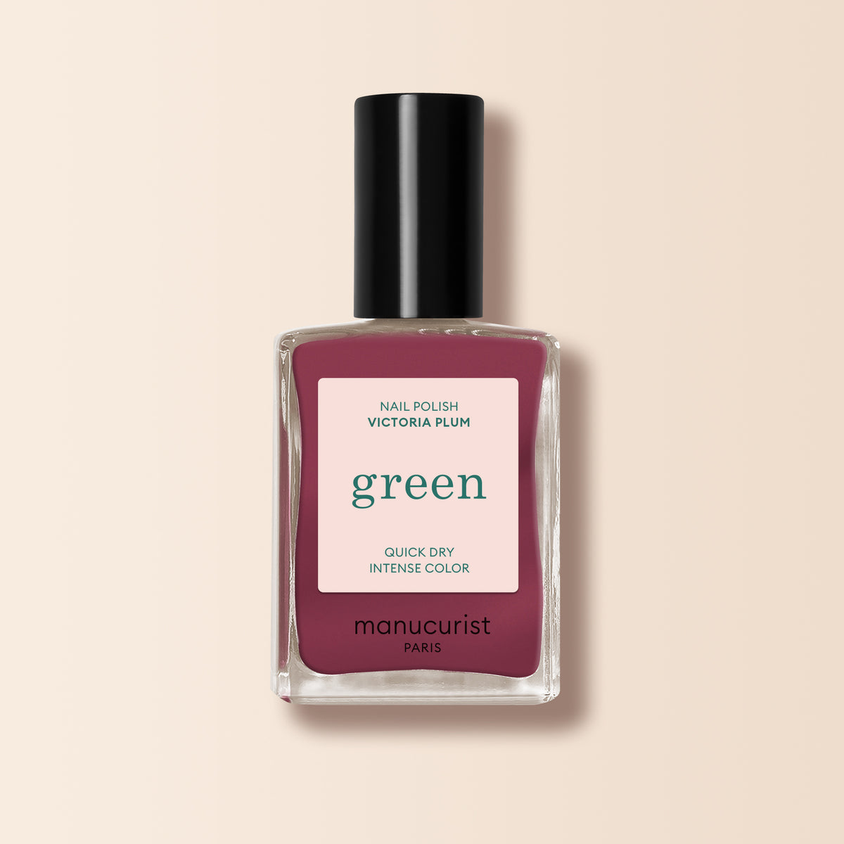A bottle of Manucurist nail polish in the Victoria Plum shade, a dark mauve with a black cap, is shown against a light beige background.