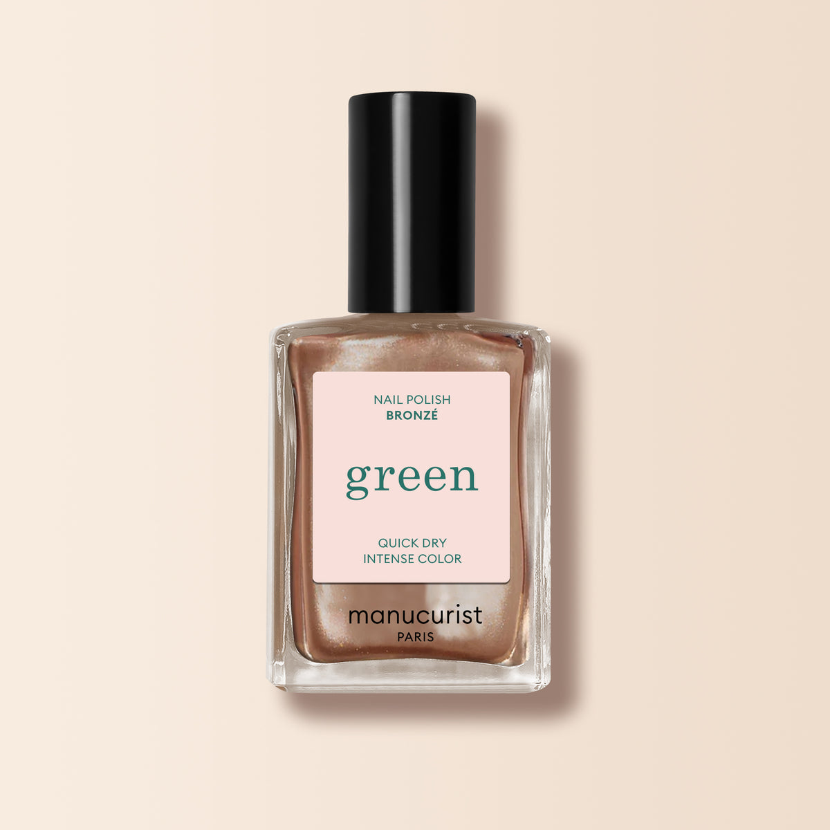 A bottle of Manucurist Bronzé nail polish with a black cap from the Green range, shown in a shimmery bronze shade against a light beige background.