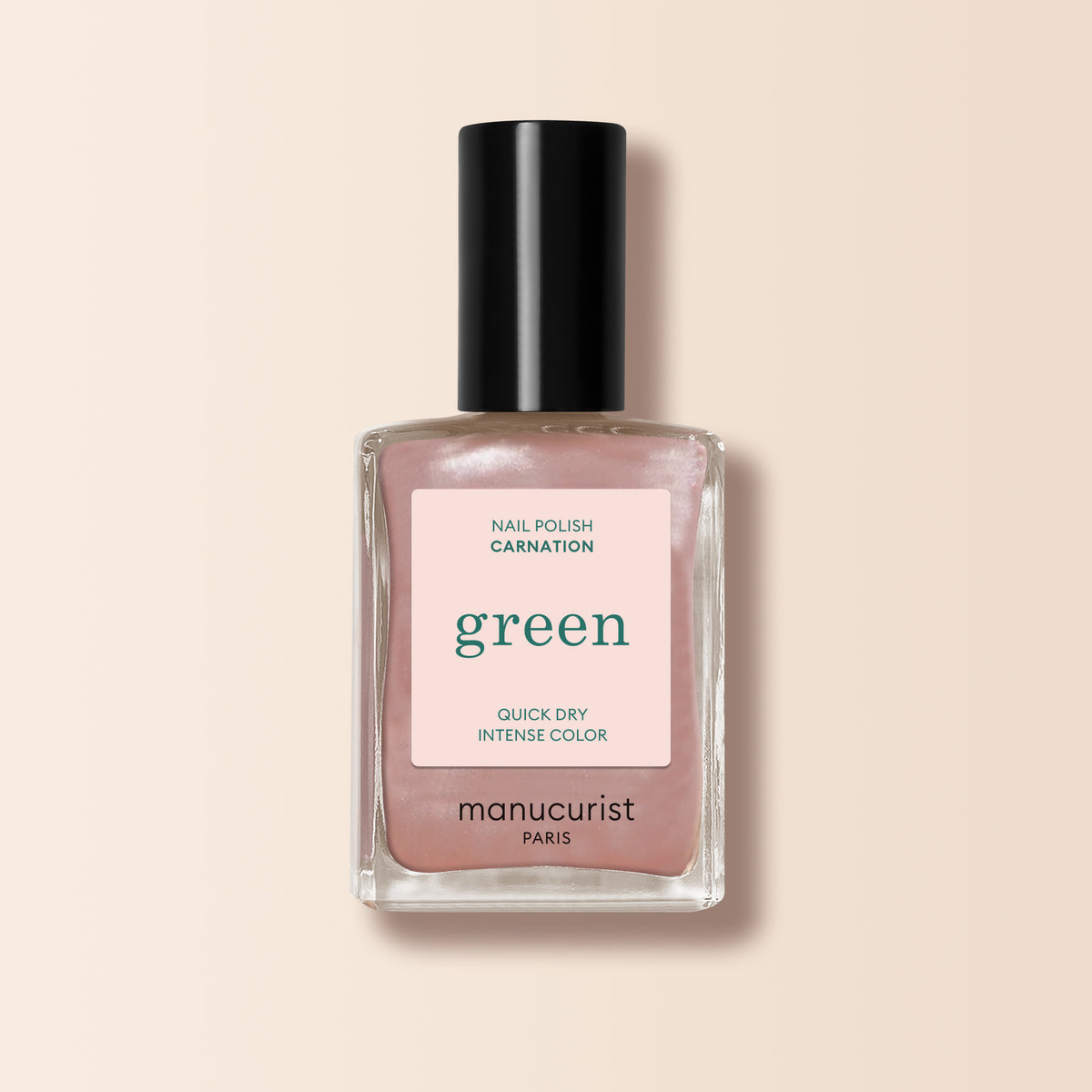 A bottle of Manucurist Carnation nail polish features a pearly pink beige shimmer, labeled "green, quick dry, intense color," with a black cap and set against a beige background.