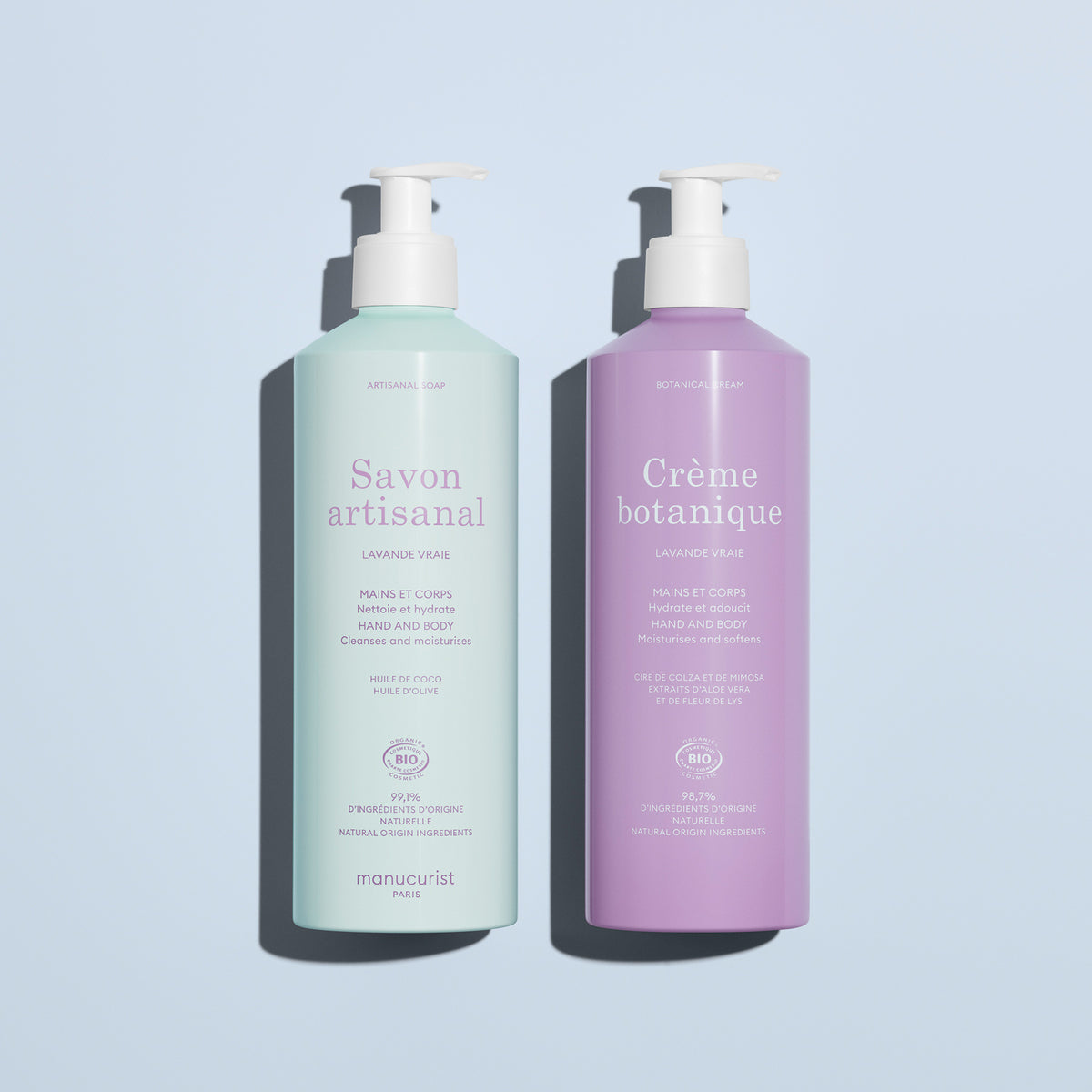 Two pastel Manucurist bottles with French labels sit side by side on a light blue surface. The lavender bottle is Soothing Lavande Hand  Body Cream - Cosmos Organic, offering artisan care for hands and body.