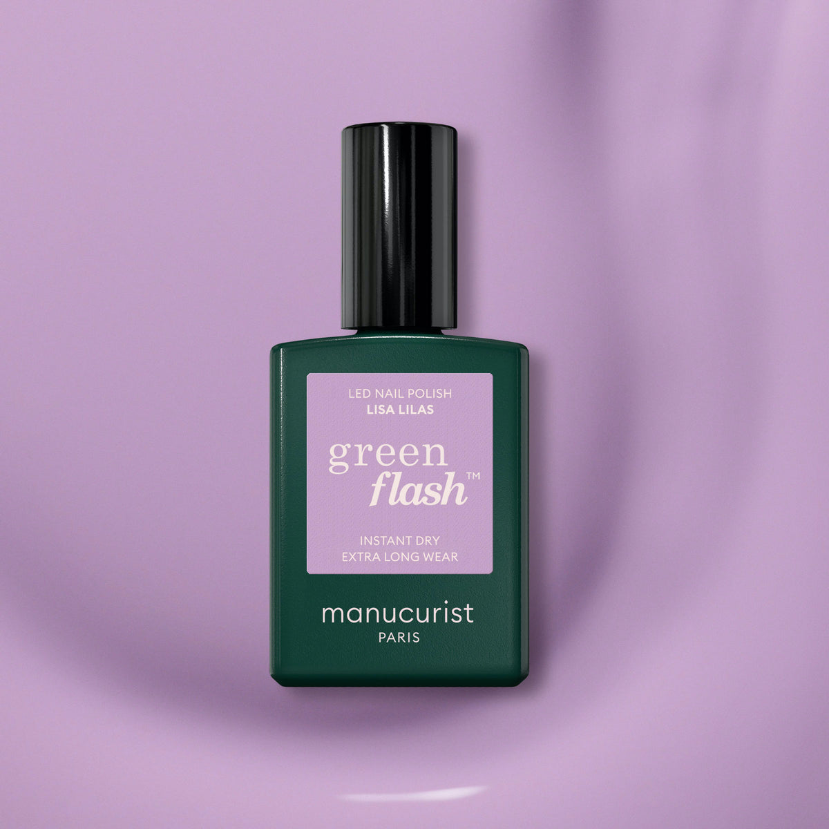 A chic bottle of Manucurist Lisa Lilas gel polish rests on a shiny, light purple surface. The dark green bottle with black cap and lilac label highlights this elegant lilac shade from Manucurist.