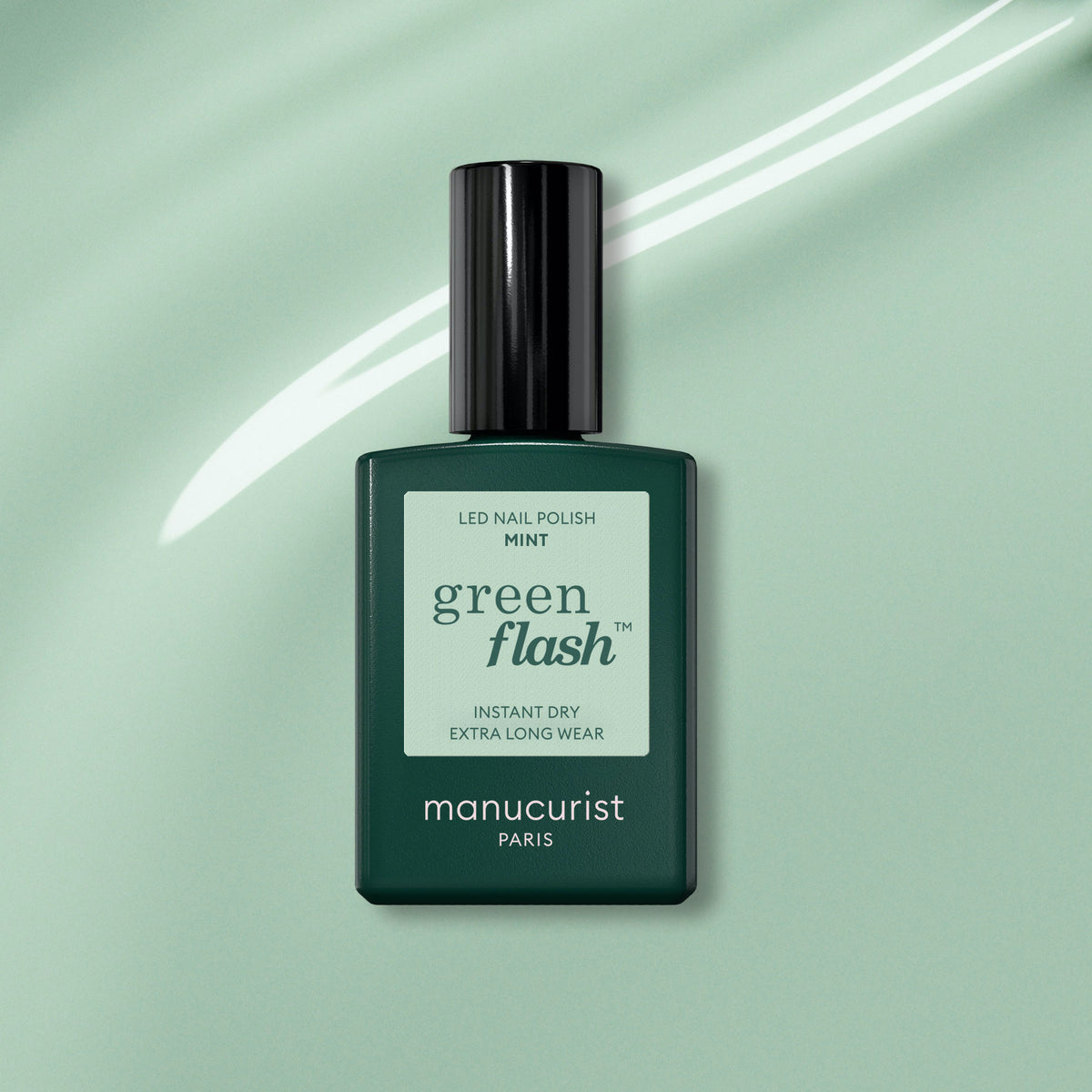 A bottle of Manucurist Mint Green Flash gel polish, featuring a sleek rectangular design and black cap, is centered on a light green background with a white streak.
