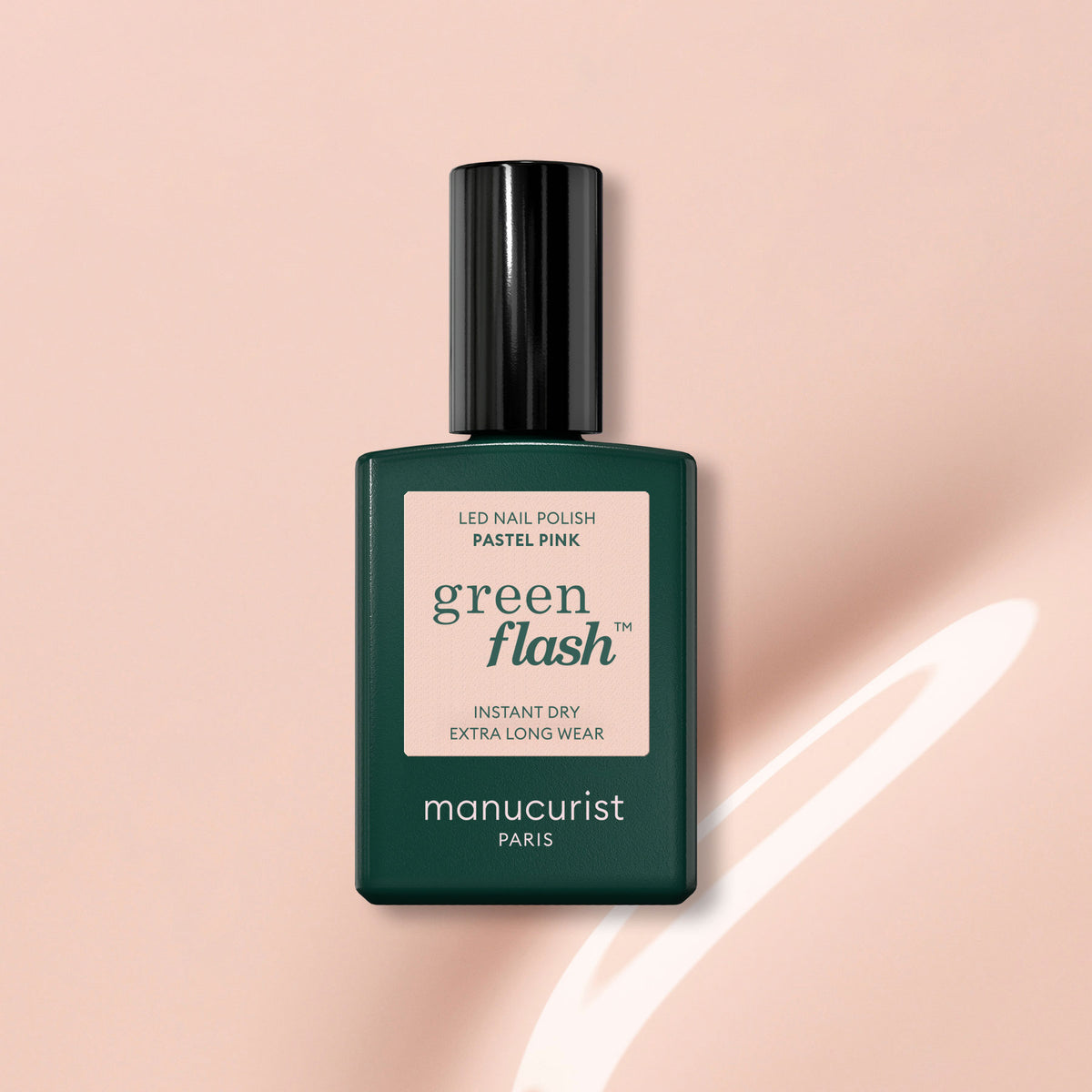 A bottle of Manucurist Pastel Pink Green Flash gel polish with a dark green cap and label is set on a light pink background, featuring a soft shadow and streaks of light.