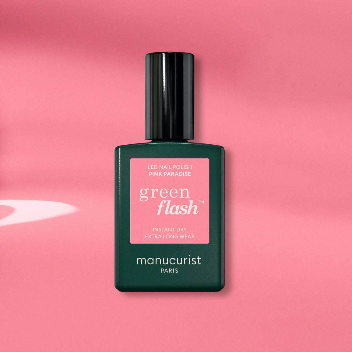 Manucurist’s Pink Paradise Green Flash gel polish is shown against a pink background. The dark green bottle with a black cap features a pink label, highlighting this vibrant candy pink shade.